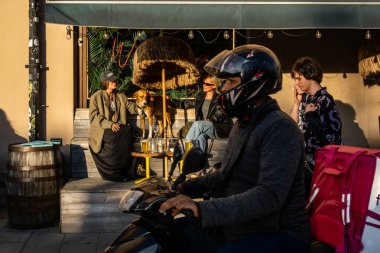 Stockholm, İsveç 'te köpekli iki kadın Hornstull bölgesindeki bir açık bar ve restoranda yemek dağıtımı ve yayalar için oturuyorlar..