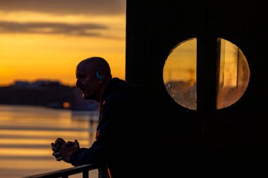 Stockholm, İsveç Baltık Denizi ve Kvarnholmen bölgesindeki güneşin doğuşuna bakan bir korkulukta dinleniyor..
