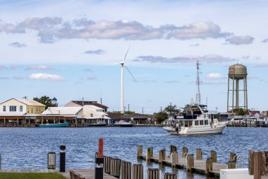 Crisfield, Maryland, USA Sept 4, 2024 A view of the port with boats, a water tower and a wind turbine. clipart