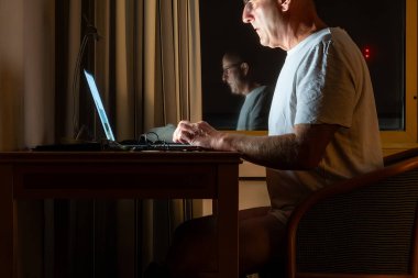 Riga, Letonya 'da gece geç saatlerde bilgisayar tarafından aydınlatılmış bir adam masa başında çalışıyor..