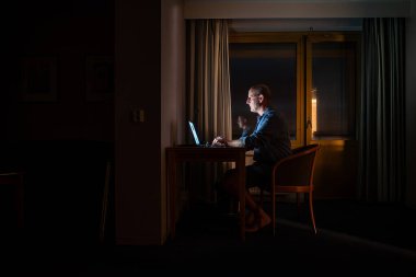 Riga, Letonya 'da gece geç saatlerde bilgisayar tarafından aydınlatılmış bir adam masa başında çalışıyor..