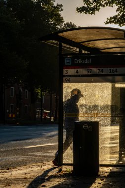 Stockholm, İsveç 12 Eylül 2024. Ringvagen 'de sabahın erken saatlerinde otobüs durağında siluetli bir adam..