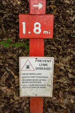 Solomons, Maryland, USA A red sign in the Calvert Cliffs State Park and the Grays Creek on the Chesapeake Bay tells people how to prevent lyme disease. clipart