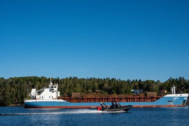 Stockholm, İsveç 14 Eylül 2024 Bir gemi dolusu taze kereste ve sürat teknesi taşıyor. .