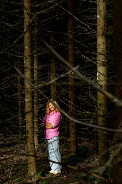 Stockholm, İsveç Pembe gömlekli ve kotlu bir kadın çalılık bir ormanda duruyor.