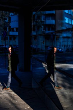 Stockholm, İsveç 17 Ekim 2024 Karlavagen 'daki Garnisonen modern bölgesinde yürüyen bir adam pencereye yansıyor..
