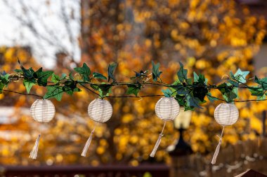 Mariefred, Sweden Small lanterns hanging on a patio and autumn foliage. clipart