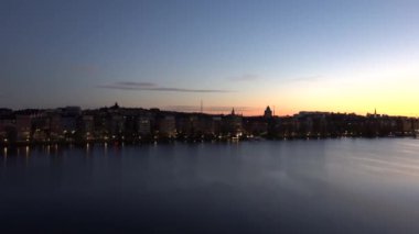 Stockholm, İsveç. Malaren Gölü 'ndeki Riddarfjarden körfezi üzerinde gün doğumu manzarası ve Batı Köprüsü' nden Belediye Binası ve Gamla Stan.. 