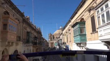 Mosta, Malta. Hareket halindeki bir otobüsten ana caddedeki konut binalarının görüntüsü.. 