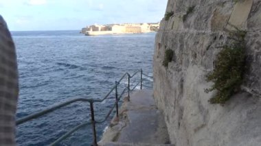 Valletta, Malta Erkek bir turist Akdeniz 'deki kayalıkların altında dar bir patika boyunca yürüyor. 