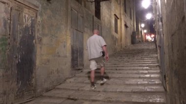 Valletta, Malta 'da bir erkek turist Kuzey Caddesi' ndeki Old Valletta 'da eski basamaklarda yürüyor.. 