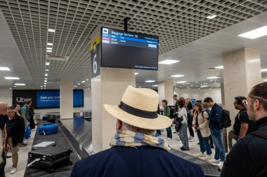 Valletta, Malta 1 No.2024. Şapkalı bir adam diğer turistlerle birlikte Malta Havaalanı 'ndaki bagaj bölümünde duruyor..