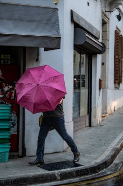 Sliema, Malta No: 7, 2024 Yağmurda elinde şemsiyeyle bir adam köşeyi dönüyor..