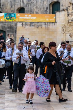 Valletta, Malta No: 7, 2024 Elbiseli hoş bir kız Old Valletta 'da bir bandonun önünde şemsiyeyle oynuyor..