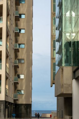 İnsanlar Tigne Point İyonu 'ndaki iskan binaları arasında yürüyorlar. Sliema bölgesi.