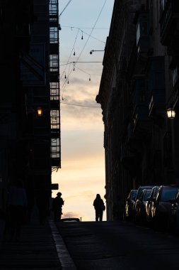 Valletta, Malta 7 Kasım 2024 Eski Valletta 'daki dik ve dar St. Ursula Caddesi' nde insan siluetleri.