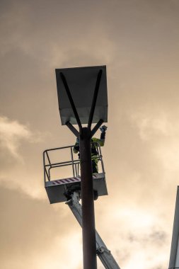 Stockholm, İsveç 20 Kasım 2024 Bir şehir işçisi Liljeholmskajen 'de bir gökdelen üzerinde yağmur örtüsünün altını temizliyor.