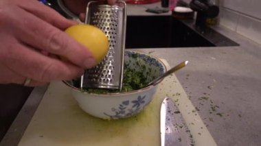 Stockholm, İsveç 'te bir aşçı Gremolata yapmak için limon rendeliyor..