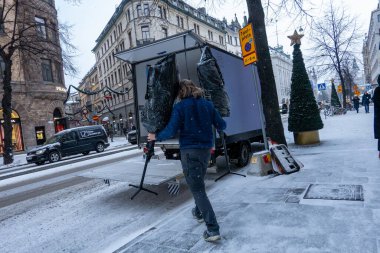 Stockholm, İsveç 21 Kasım 2024 Bir adam plastiğe sarılı iki mankeni Birger Jarlsgatan şehir merkezinde park halindeki bir kamyona taşıyor..