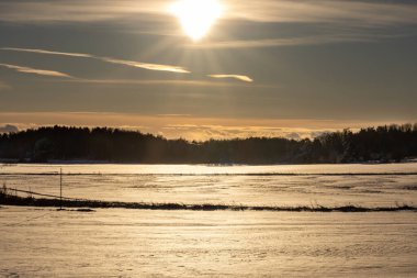Gamla Uppsala, İsveç Kraliyet Tepeleri yakınlarında gün batımında buzlu bir kışın manzarası.
