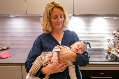 Stockholm, İsveç 'te bir büyükanne kucağında bir aylık bir torun tutuyor..