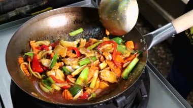 Stockholm, İsveç. Bir aşçı tavada büyük bir Tayland baharatlı kızartma yapar. Tavuk parçaları ve taze sebzelerle.. 