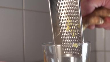 Mutfakta bir adam taze zencefili bardağa dolduruyor.. 