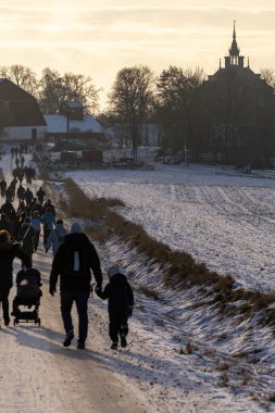 Uppsala, İsveç 7 Aralık 2024 İnsanlar Wik 's Castle' daki geleneksel Noel pazarına doğru karda kırsal bir yolda yürüyor.