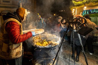 Riga, Letonya 9 Aralık 2024 Yılbaşı Pazarı 'nda bir kişi açık ateş üzerinde yemek hazırlıyor..