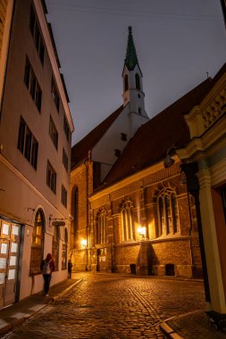 Riga, Letonya 10 Aralık 2024 'te yayalar sabahın erken saatlerinde aydınlatılmış St. John Kilisesi' nin önünden geçtiler.