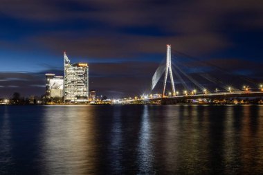 Riga, Letonya 10 Aralık 2024. Swedbank kulesi ve Daugava Nehri 'nin gece manzarası.