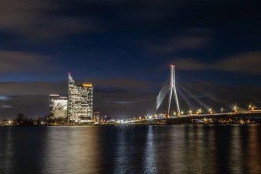 Riga, Letonya 10 Aralık 2024. Swedbank kulesi ve Daugava Nehri 'nin gece manzarası.