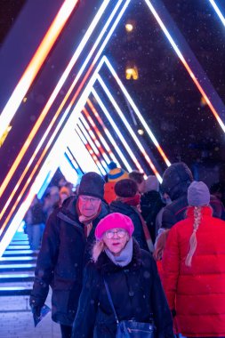 Stockholm, Sweden December 15, 2024 Pedestrians at night explore The Wave, an art light installation during the Nobel Light Week 2024 on Norrbro. clipart