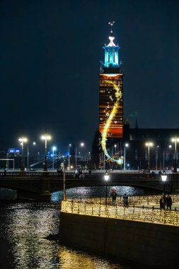 Stockholm, İsveç 15 Aralık 2024 Nobel Işık Haftası boyunca aydınlık belediye binasının veya Stadshuset 'in önünden geçen insanlar.