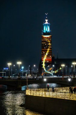 Stockholm, İsveç 15 Aralık 2024 Nobel Işık Haftası boyunca aydınlık belediye binasının veya Stadshuset 'in önünden geçen insanlar.