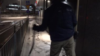 Stockholm, İsveç 'te bir adam sabahın erken saatlerinde bir iskan yolunda kar küremek için kar küreği kullanıyor.. 