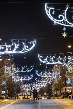 Vilnius, Lithuania Jan 3, 2025 Pedestrians walk at night on Gedimino Street with Christmas ornamanets, clipart