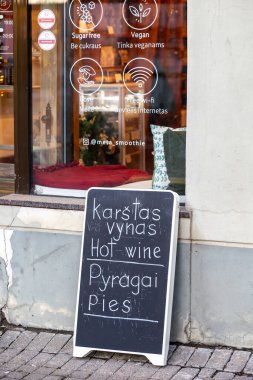 Vilnius, Litvanya 4 Ocak 2025 Bir dükkanın önünde bir karatahta tabelası İngilizce ve Litvanyaca sıcak şarap ve turta sunuyor.