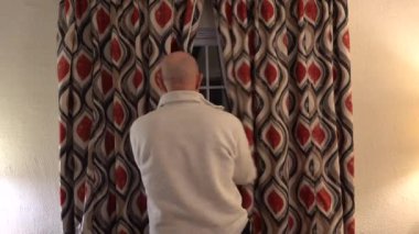 Solomonlar, Maryland USA Bir adam yatak odasındaki perdeleri kışın dışarıdaki karanlığa açar..