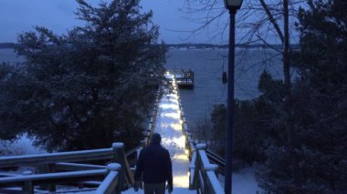 Solomonlar, Maryland USA Bir adam geceleyin Patuxent Nehri 'nde karlı bir rıhtımda yürüyor. 