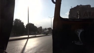 Kahire, Mısır. Bir tuktuk motorlu scooter Helwan banliyösünde trafikten geçiyor..