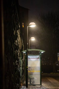 Stockholm, İsveç 20 Ocak 2025. Sisli bir gecede Sodermalm 'de bir kişi otobüs durağında bekliyor..
