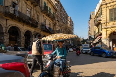 Kahire, Mısır 22 Ocak 2025. Genç bir adam motosikletle taze ekmek getiriyor. Kafasını dengeleyerek..