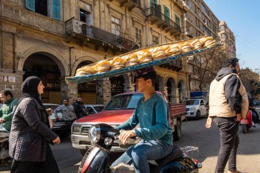 Kahire, Mısır 22 Ocak 2025. Genç bir adam motosikletle taze ekmek getiriyor. Kafasını dengeleyerek..