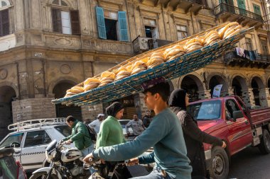 Kahire, Mısır 22 Ocak 2025. Genç bir adam motosikletle taze ekmek getiriyor. Kafasını dengeleyerek..