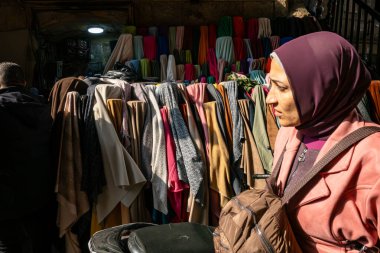 Kahire, Mısır, 25 Ocak 2025 Han el Halili pazarında yürüyen Müslüman bir kadın kumaş parçalarının arasında..
