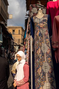 Kahire, Mısır, 25 Ocak 2025 Han el Halili pazarında yürüyen Müslüman bir kadın kumaş parçalarının arasında..