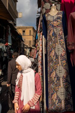 Kahire, Mısır, 25 Ocak 2025 Han el Halili pazarında yürüyen Müslüman bir kadın kumaş parçalarının arasında..