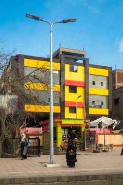 İskenderiye, Mısır 28 Ocak 2025 Bir kadın İskenderiye 'nin dışındaki renkli binalarda tren peronunda yürüyor.