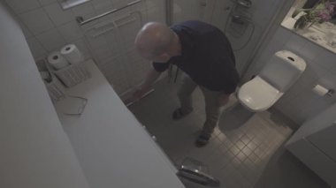 Stockholm, İsveç 'te bir adam çamaşır makinesinden ev içi tuvaletteki kurutucuya kıyafet değiştirir.. 